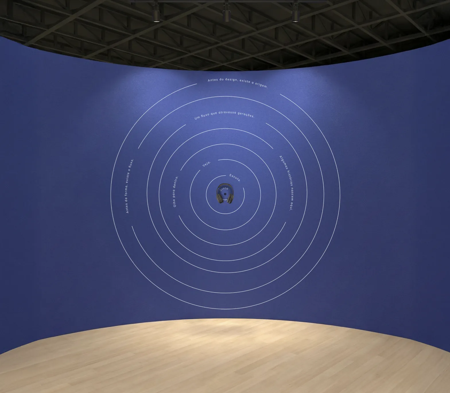 Estudo da parede da área imersiva: círculos concêntricos em linha branca sobre o azul, com frases como “Antes do design, existe a origem.” e um fone de ouvido ao centro.