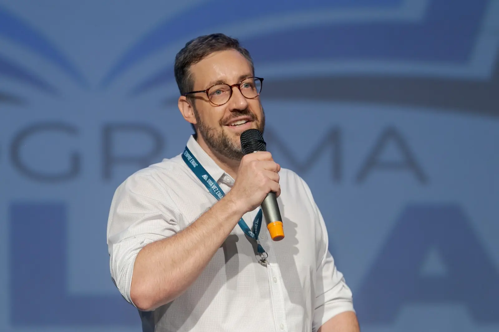 Palestrante com microfone no palco de um evento da ENIAC.