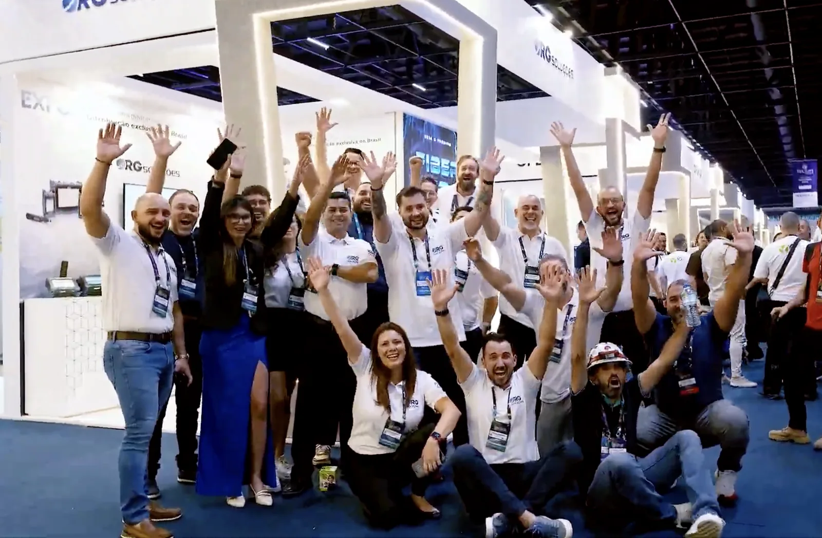 Equipe da RG Soluções comemorando em frente ao estande durante a feira.