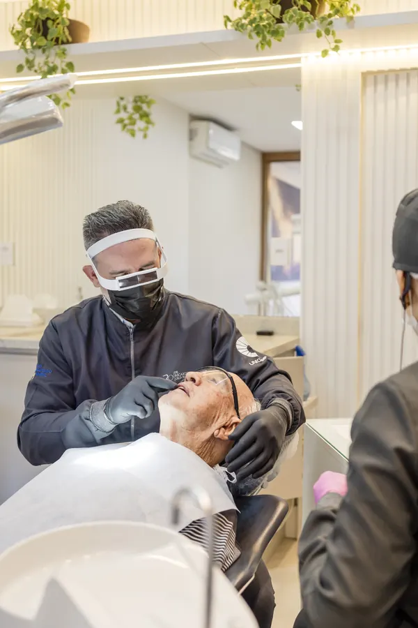Dentista em atendimento, com protetor facial.