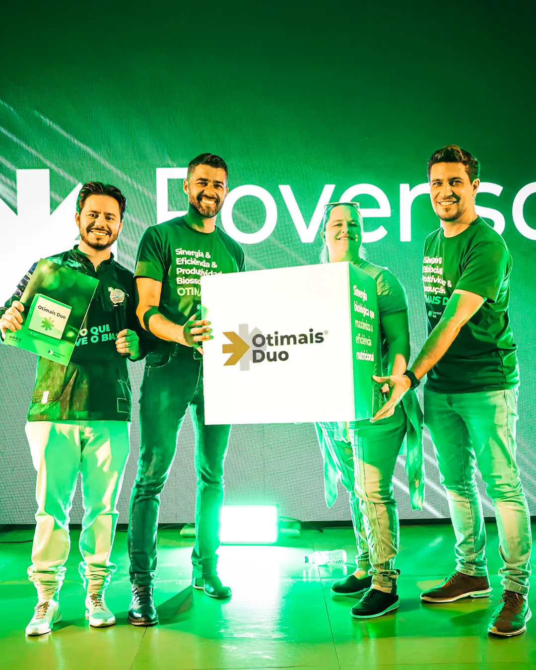 Equipe Rovensa Next no palco do lançamento do Otimais Duo, com luz verde e a placa do produto.