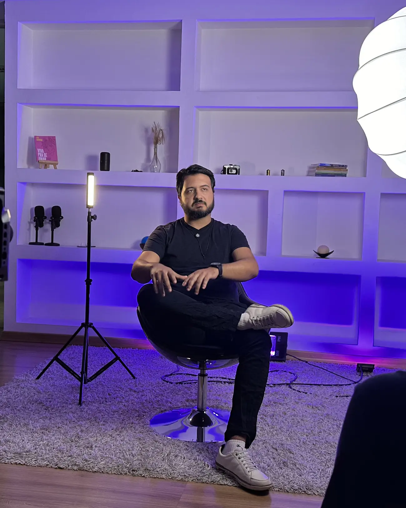 João Thiago Carvalho sentado de pernas cruzadas durante gravação no estúdio da Buzz 360.